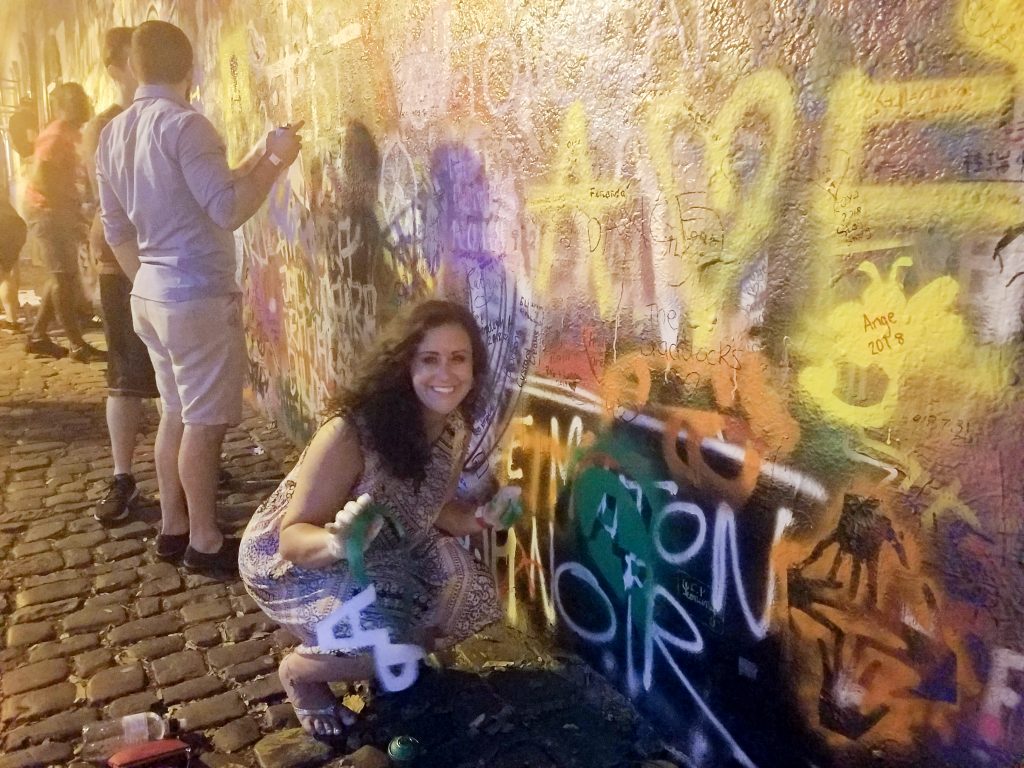Spray-painting a stencil design onto the John Lennon Wall in Prague (one of the most interesting things to do in Prague).