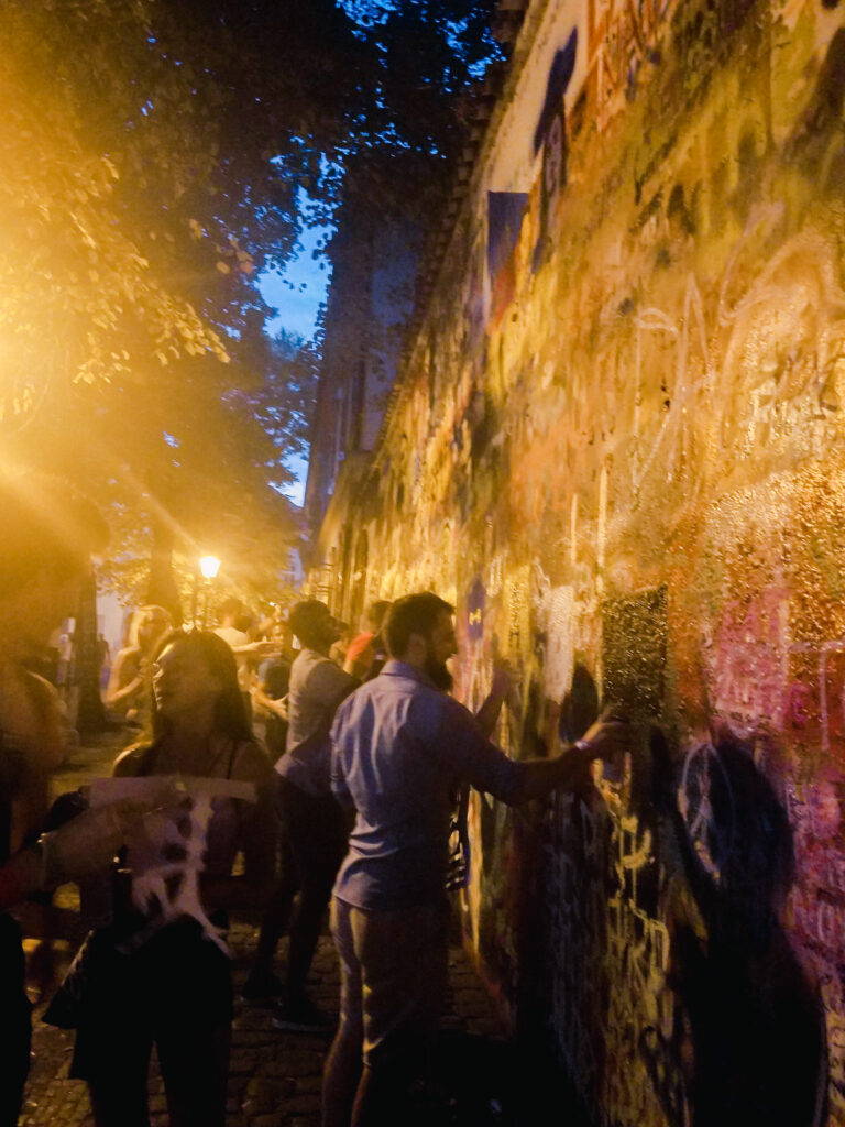 Nighttime at the John Lennon Wall in Prague, where people are spray-painting. (Doing a bar crawl is one of the most interesting things to do in Prague).