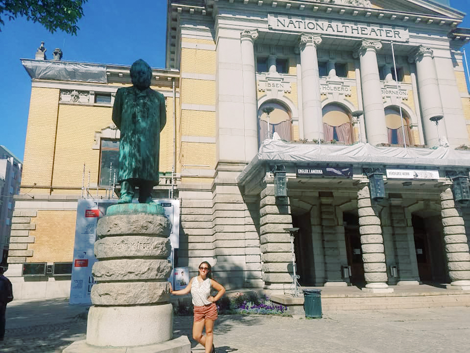 A woman poses beside a statue of Henrik Ibsen in Oslo