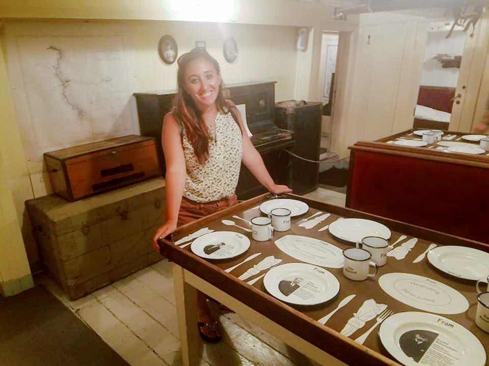A woman stands inside the dining room of a model ship 