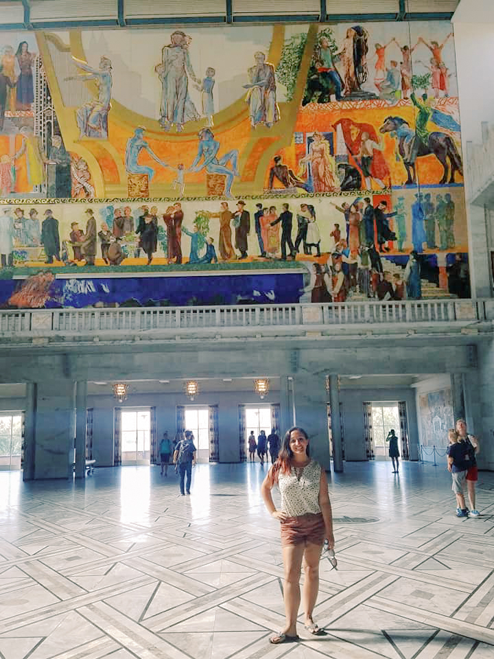 A woman poses in front of a mural in the city hall in Oslo