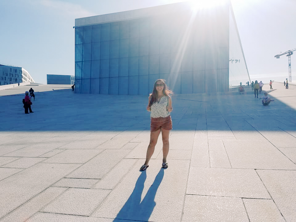 A woman stands in front of the Oslo opera house 