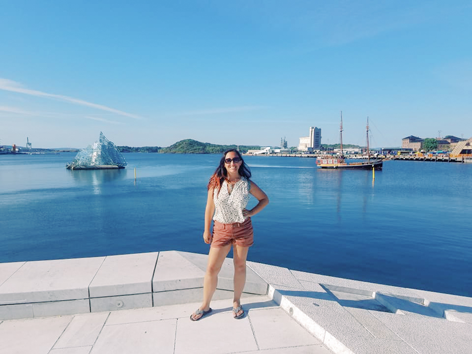 A woman poses against a backdrop of a fjord in Oslo, Norway