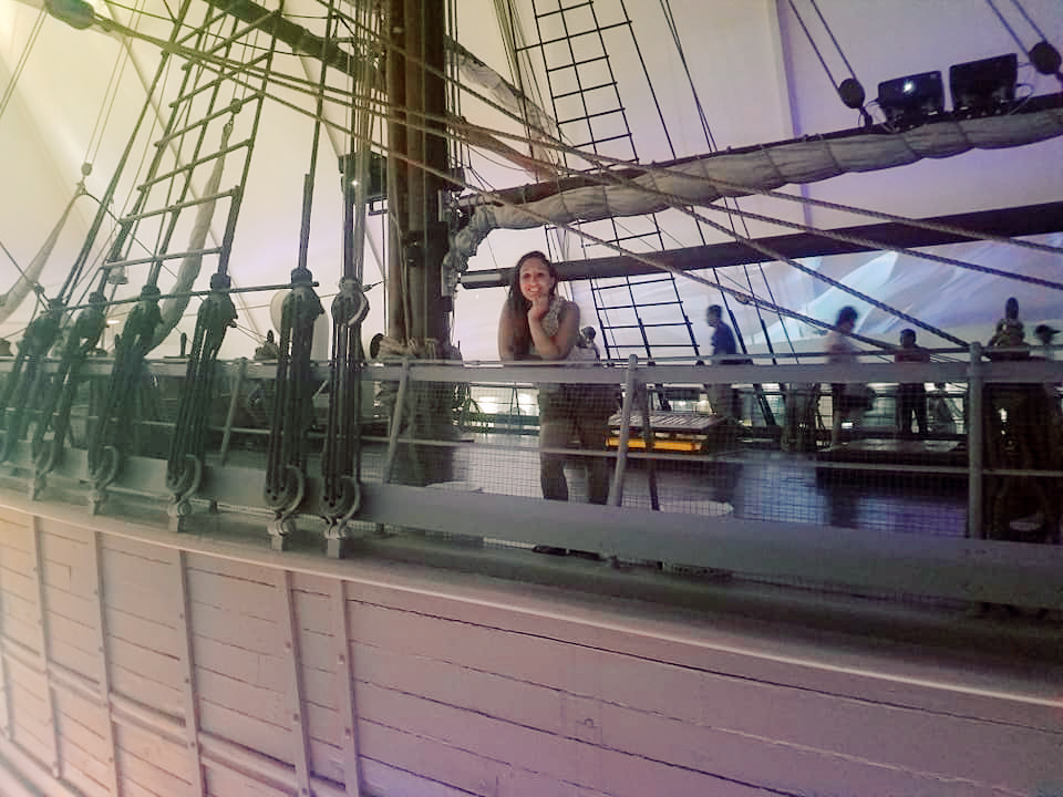 A woman poses on a model ship in a museum 