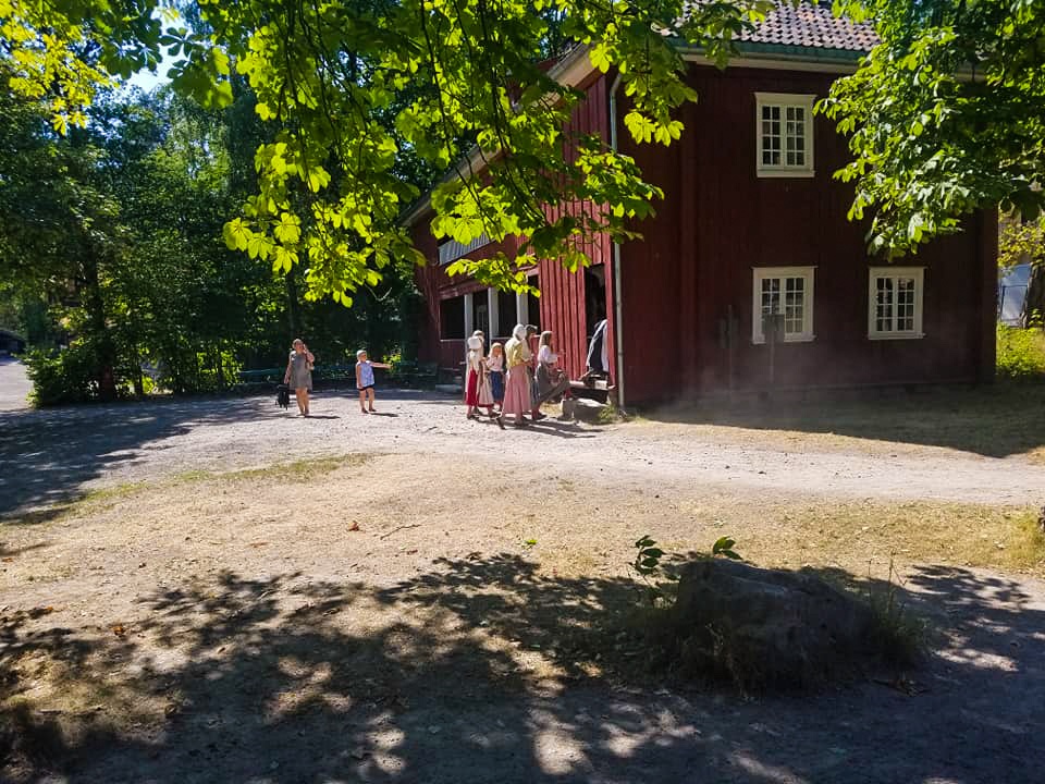 A group of costumed employees enters a building at the Outdoor Folk Museum in Oslo
