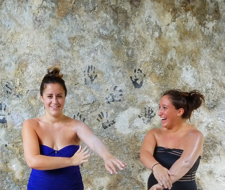 Two women applying white mud before entering the sulfur springs in Soufriere