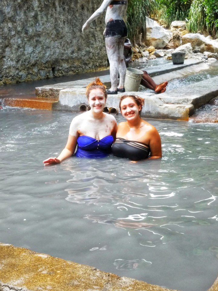 Two women in white clay masks enjoy the sulfur springs in St Lucia, they are spending one day in Soufriere 