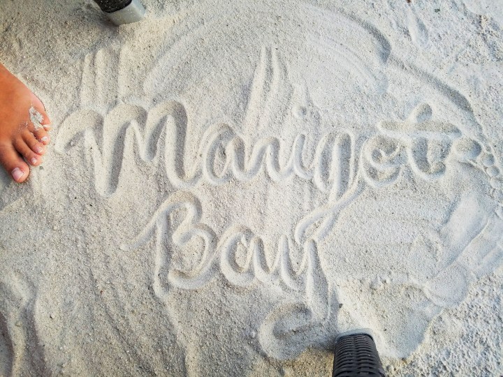 The words Marigot Bay are written in the sand