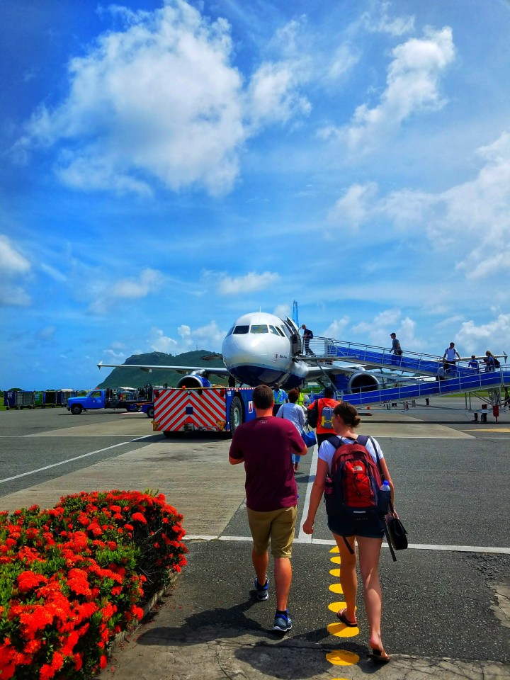 A plane sitting on a tarmac with a group of people walking towards it. Author is sad that she her trip to St Lucia with a friend is over. 