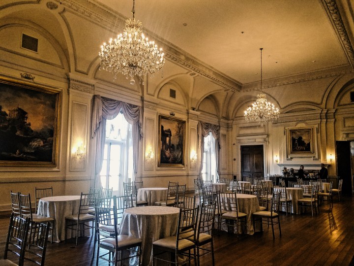 Grand ballroom with Gatsby themed chandeliers, paintings, and tables at Oheka Castle on Long Island