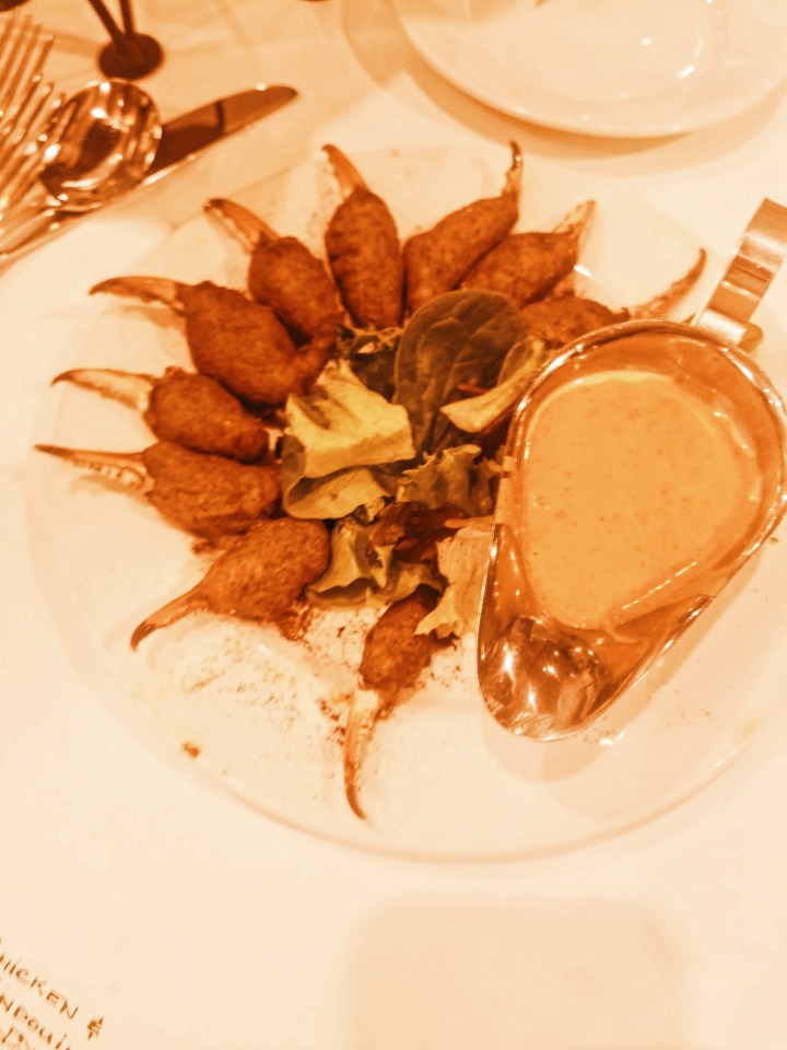 Fried crab fingers on a bed of lettuce and white plate with sriracha dipping sauce at K Paul's Kitchen in New Orelans