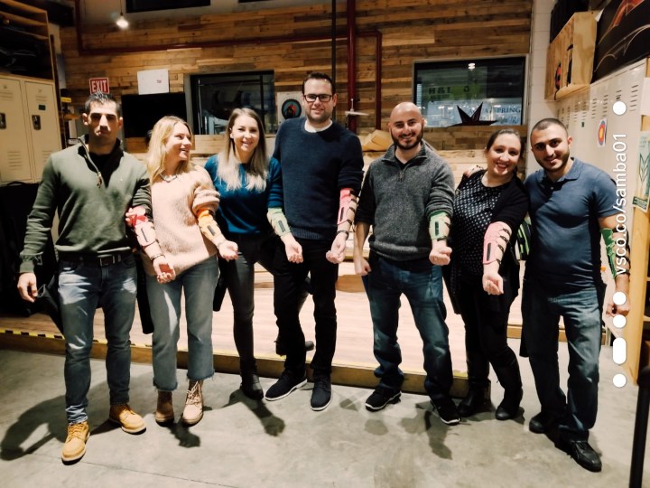 A group of four men and three women pose with wrist guards needed for an archery lesson. 