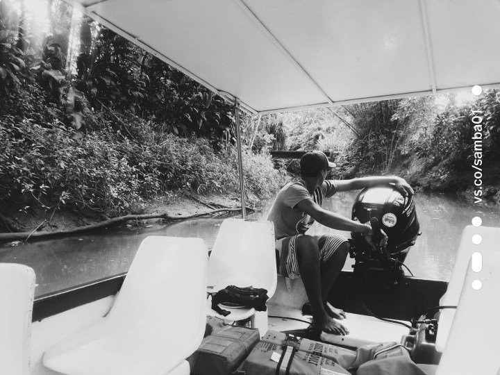 A young man in a black and white photo operates an engine for the monkey boat tour in Costa Rica.