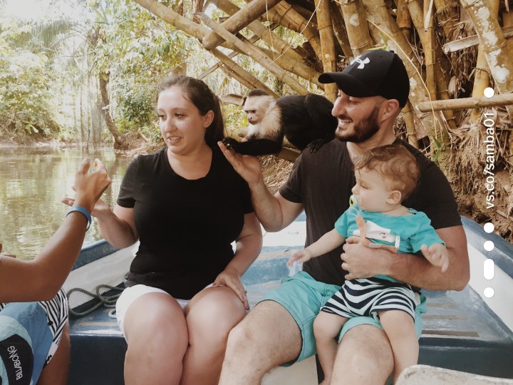 A family interacts with a small black and white monkey on the monkey boat tour in Costa Rica