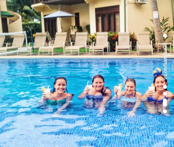 Four girls raise their glasses while sitting in a pool in Jaco, Costa Rica