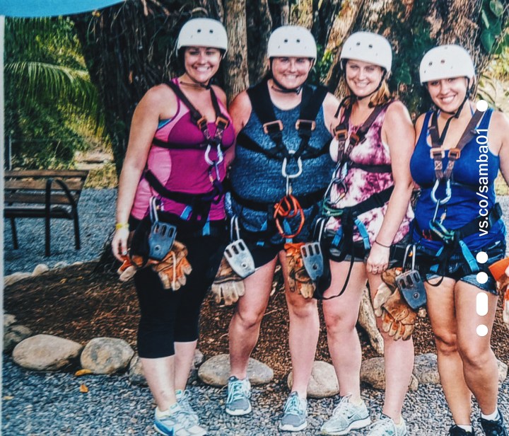 Four women pose with ziplining gear on