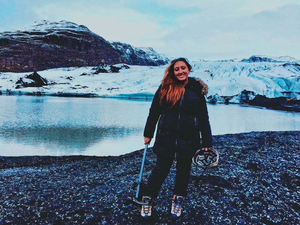 A woman stands in climbing gear at the bottom of Solheimajokull Glacier