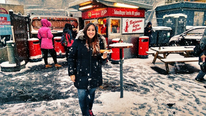 A woman standing with a hot dog in Rekyjavik