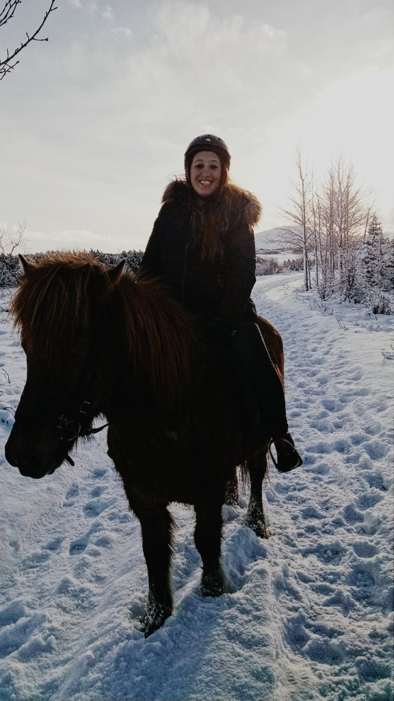 A woman rides an Icelandic horse through the snow in Iceland