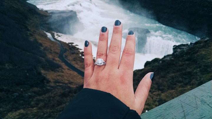 A woman showing her hand with new engagement ring over Gullfoss Falls