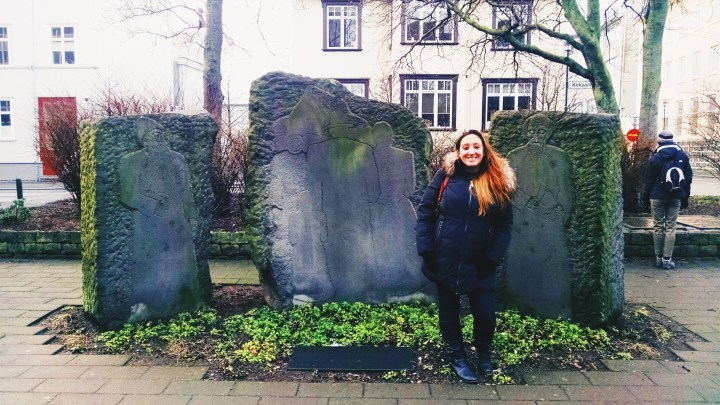 A woman standing next to a viking statue on the street