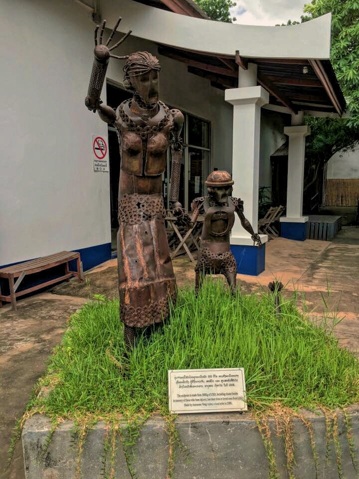 A sculpture of a woman and a child made out of UXO parts outside of the COPE Center