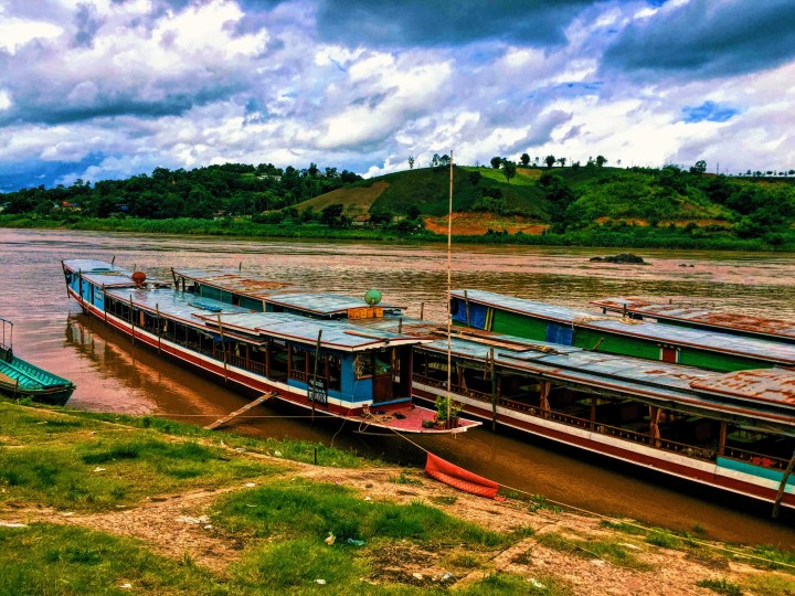 Three long slow boats pulled into port in Laos from the Mekong River