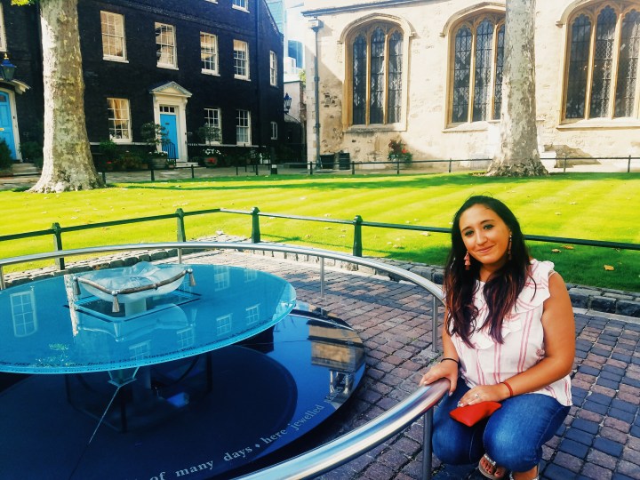 Woman squatting next to the memorial on Tower Green at Tower of London commemorating those lives lost. 