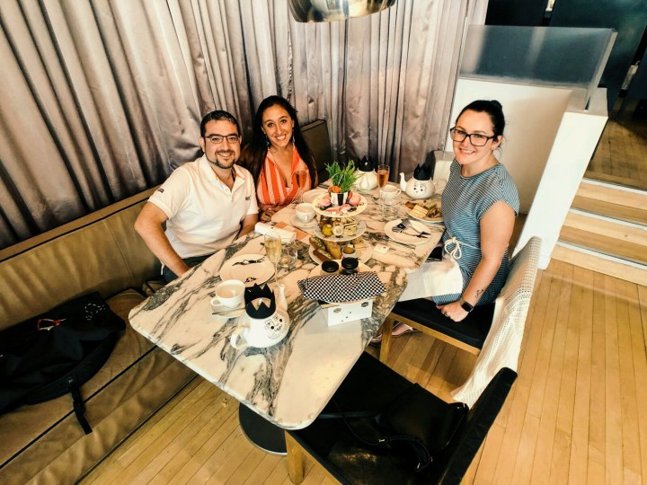 Three friends sitting at a table enjoying the Mad Hatter's Afternoon Tea in London