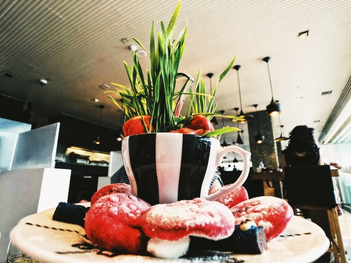 Marshmallow magic mushrooms served at the Sanderson Hotel Mad Hatter Afternoon tea party. The mushrooms are pink and white and served under a black and white striped teacup filled with grass.