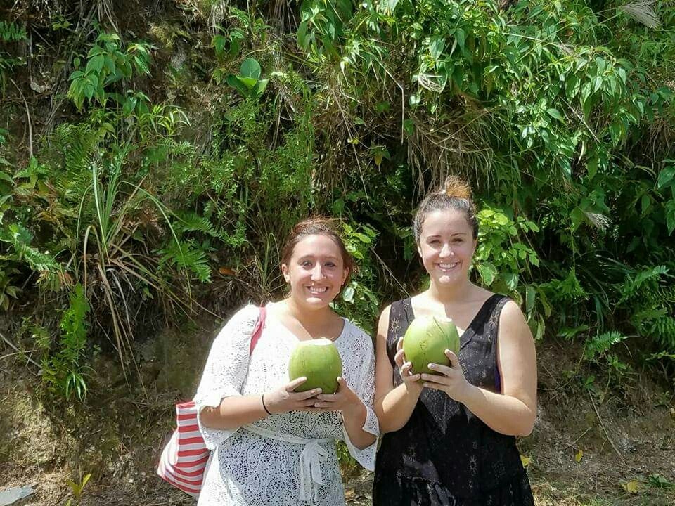 Two aliens hold coconuts that are green in St Lucia during a one day trip to Soufriere