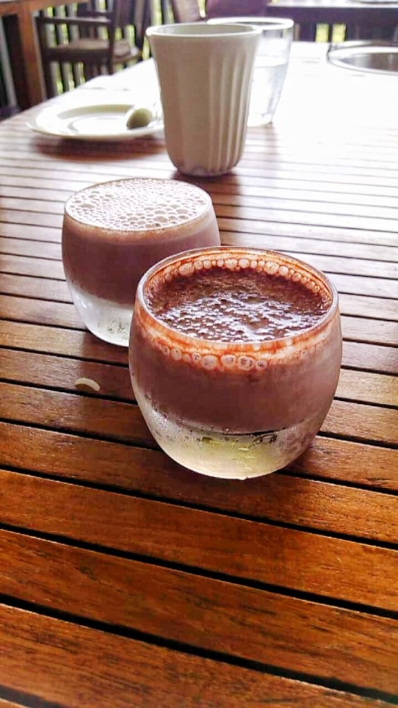 Two chocolate shots are featured on a wooden table. This restaurant, Boucan is one you should not miss if you have one day in Soufriere. 