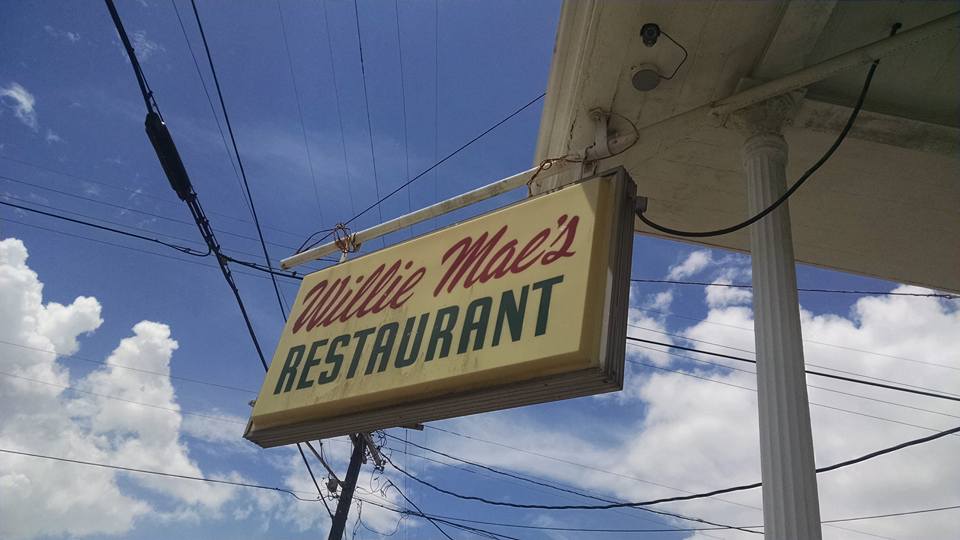 The sign for Willie Mae's Restaurant set against a blue and cloudy sky.