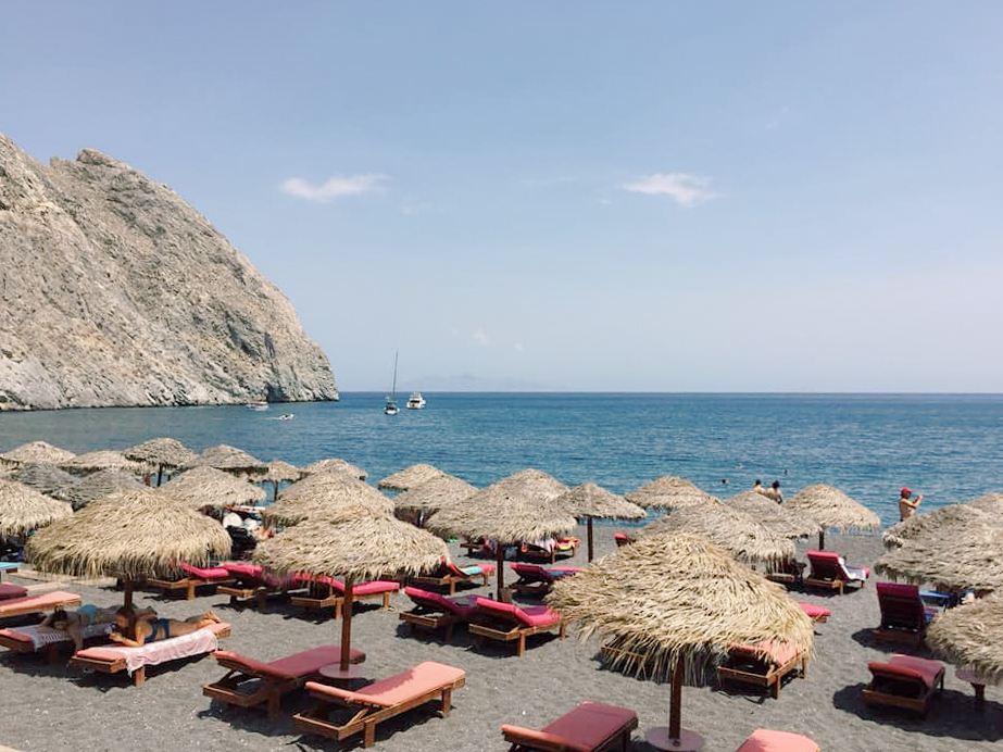 Lounge chairs and umbrellas set up on a beach in Santorini