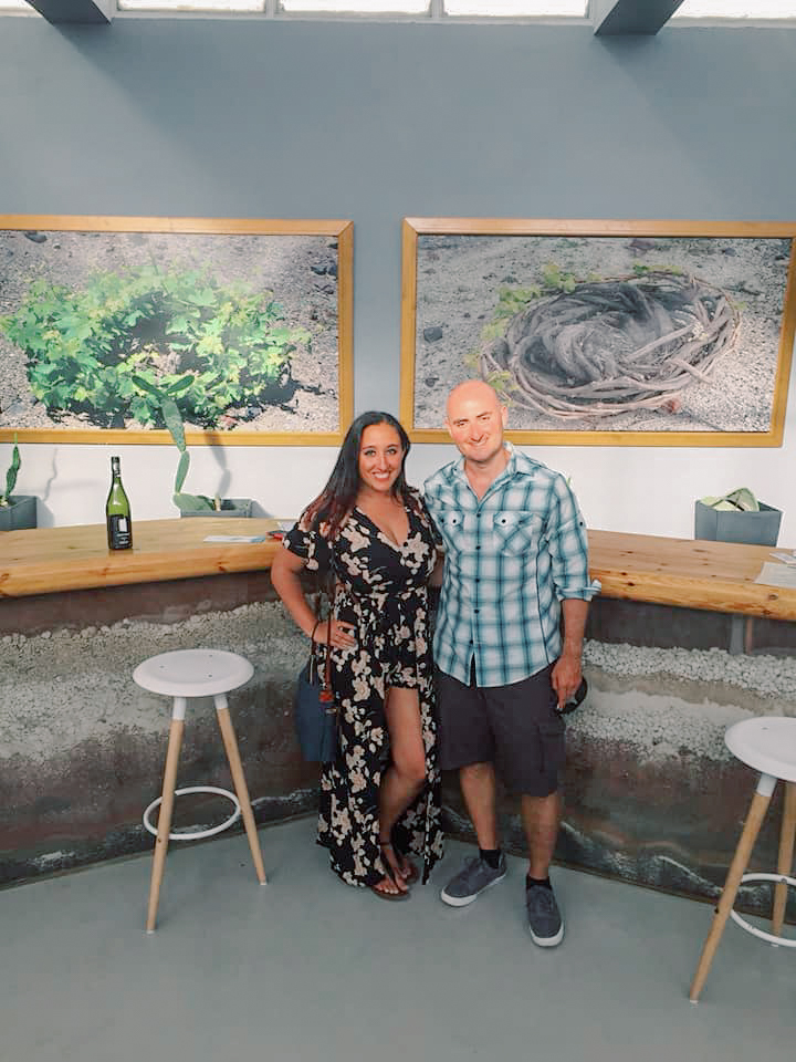 A couple posing for a photo in a room at a wine tasting in Santorini