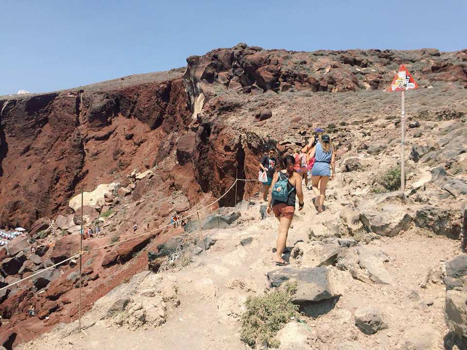 A group of hikers hiking up a cliffside in Santorini
