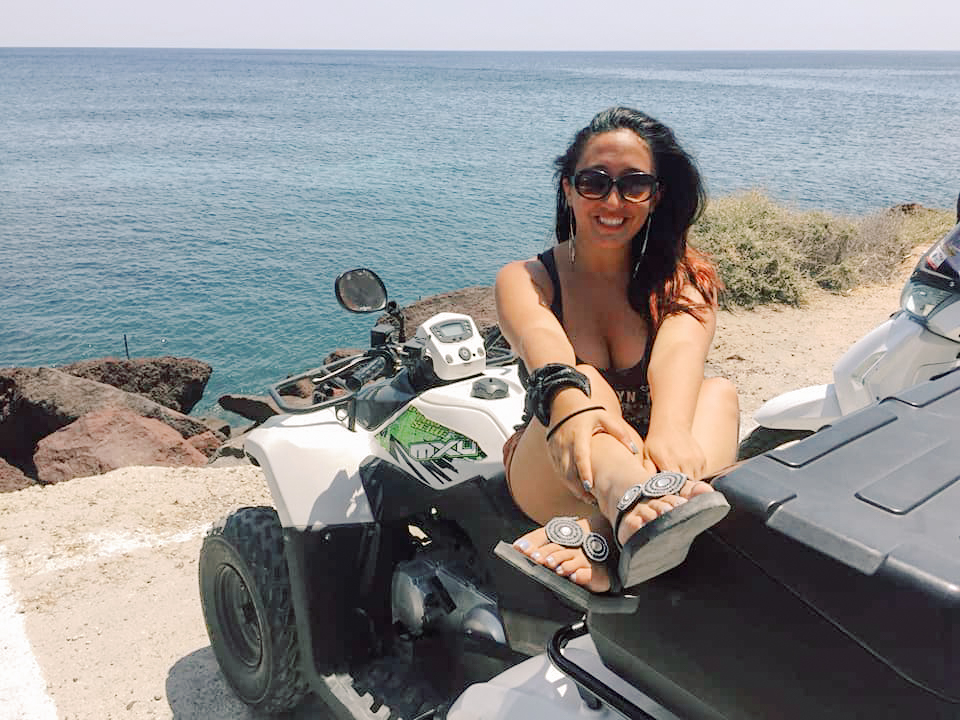 A woman sitting on a quad overlooking the ocean