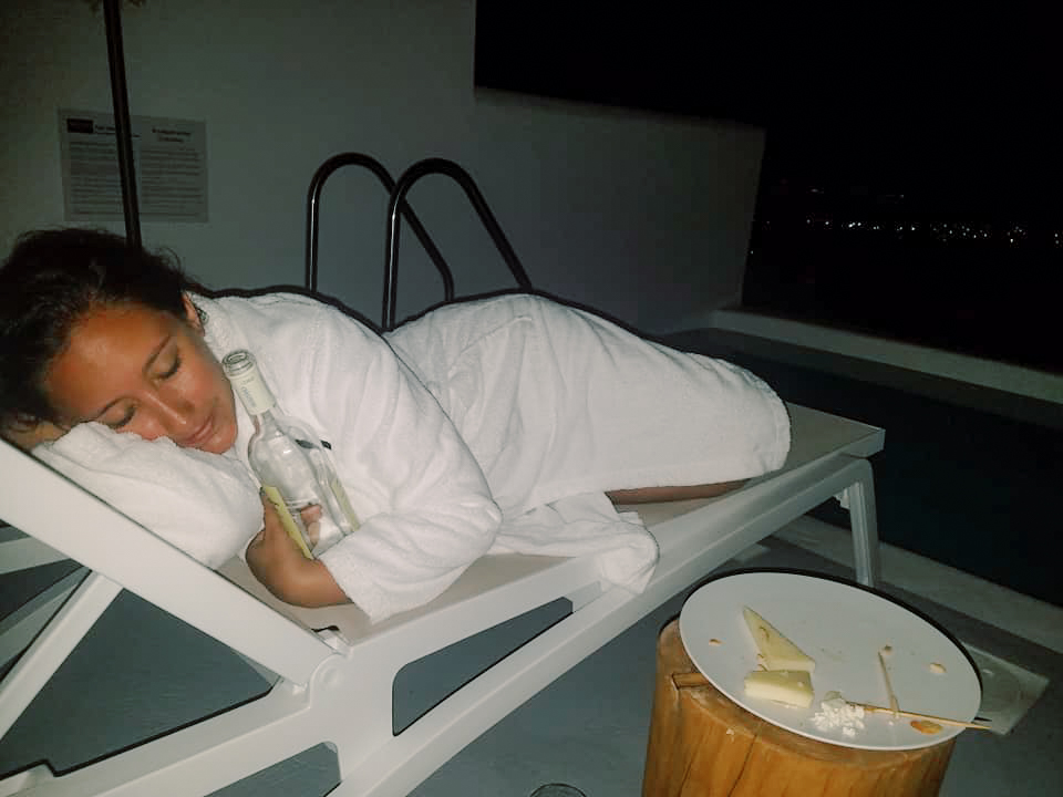 A woman lounges on a pool chair with a bottle of wine