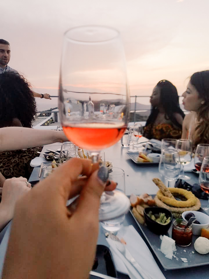 A glass of wine held up in front of the camera at a wine tasting class in Santorini