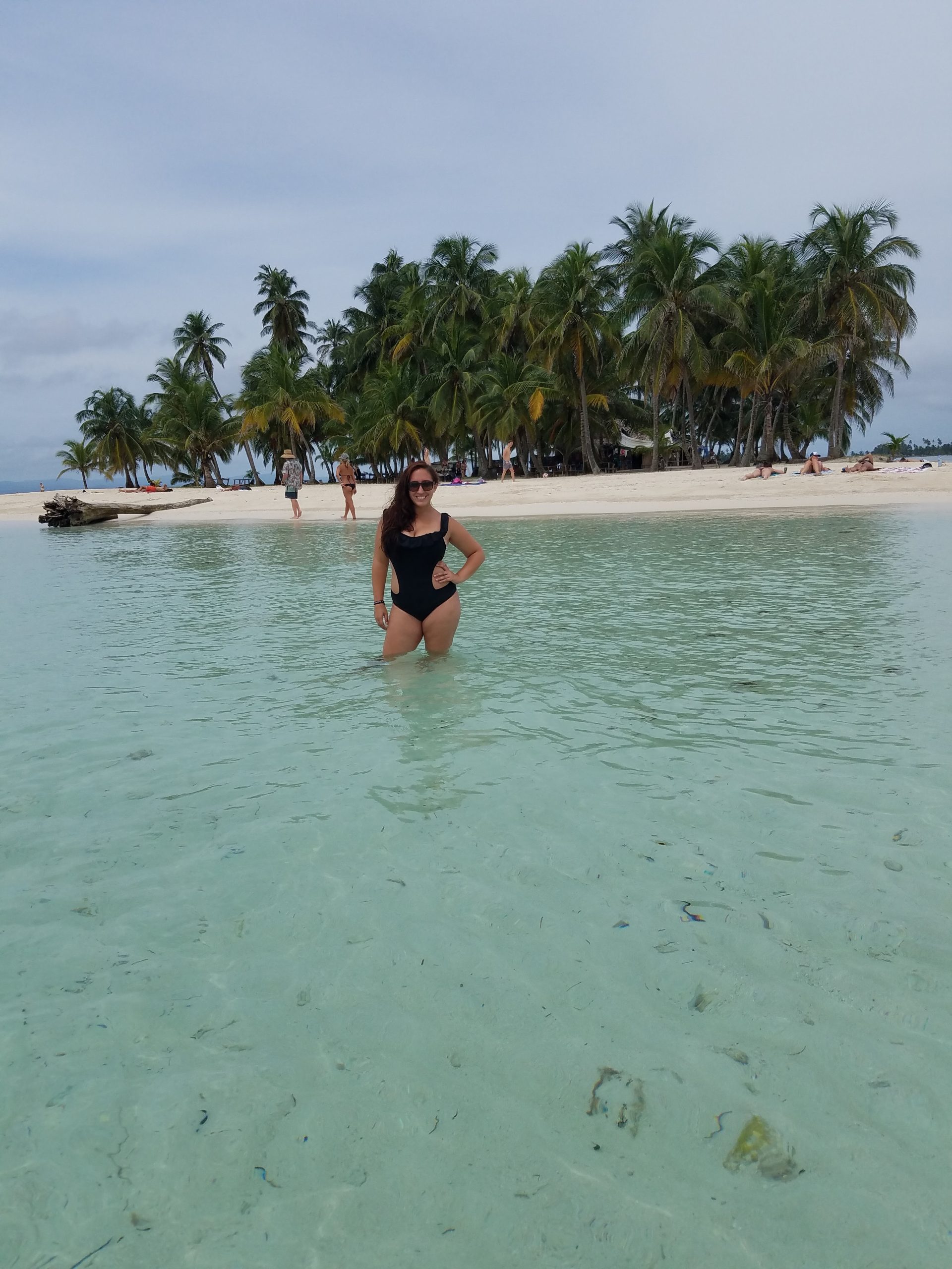 A woman standing in the water against a backdrop of an island full of palm trees