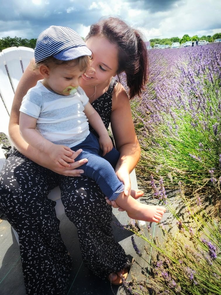 A woman and a child sit on a chair in the middle of a lavender field