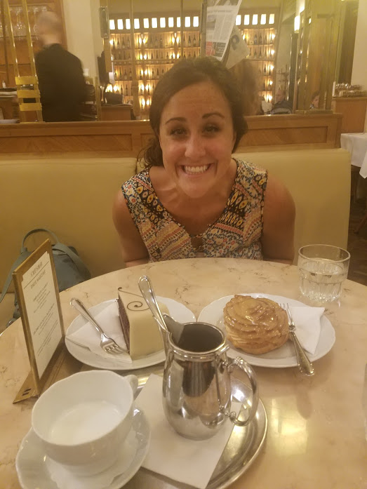 A smiling woman seated at a table of desserts