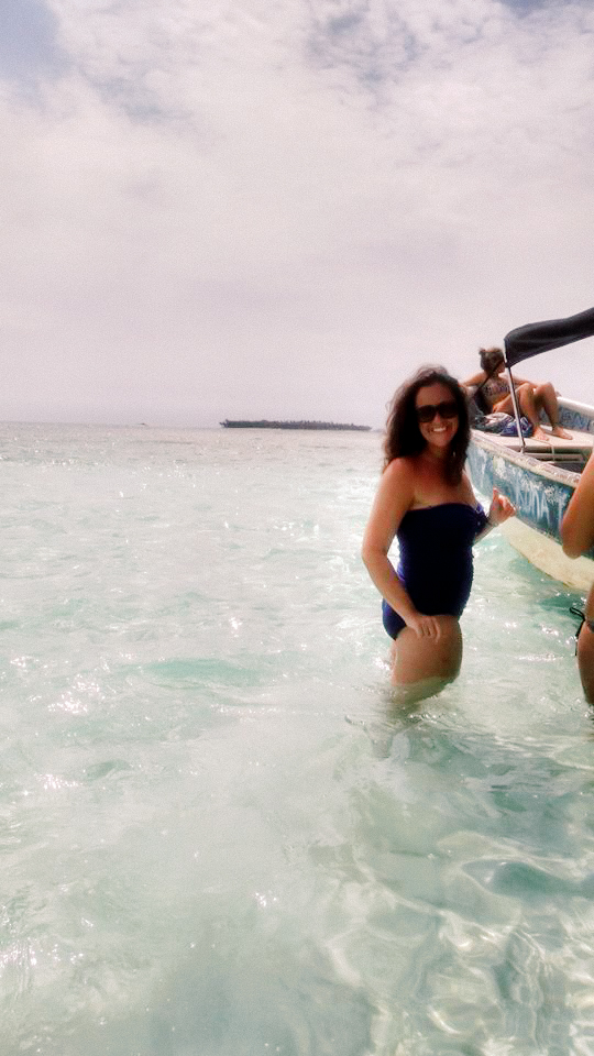 A woman standing in the water next to a boat