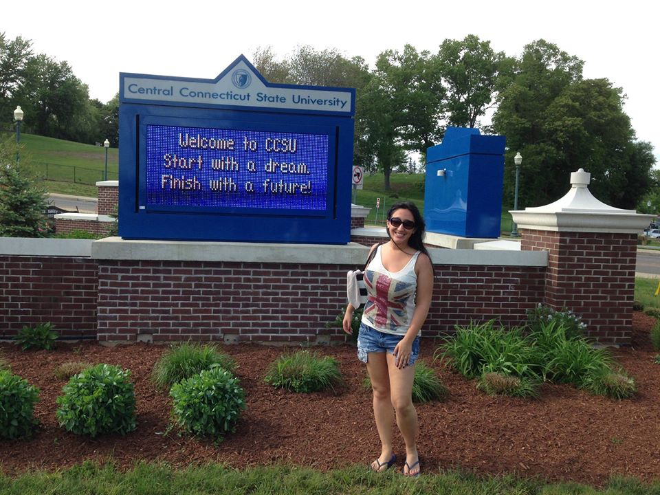 A woman stands in front of a sign for Central Connecticut State University