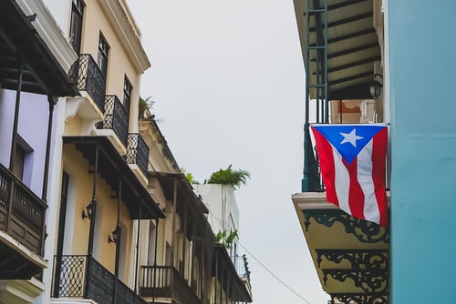 A block of buildings, one of which has the Puerto Rican flag hanging off the balcony