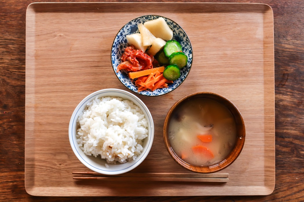Three bowls of food, one with rice, one with broth, and another with vegetables