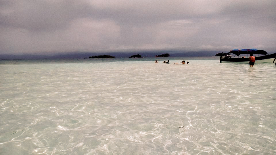 Clear water with people and several islands in the background