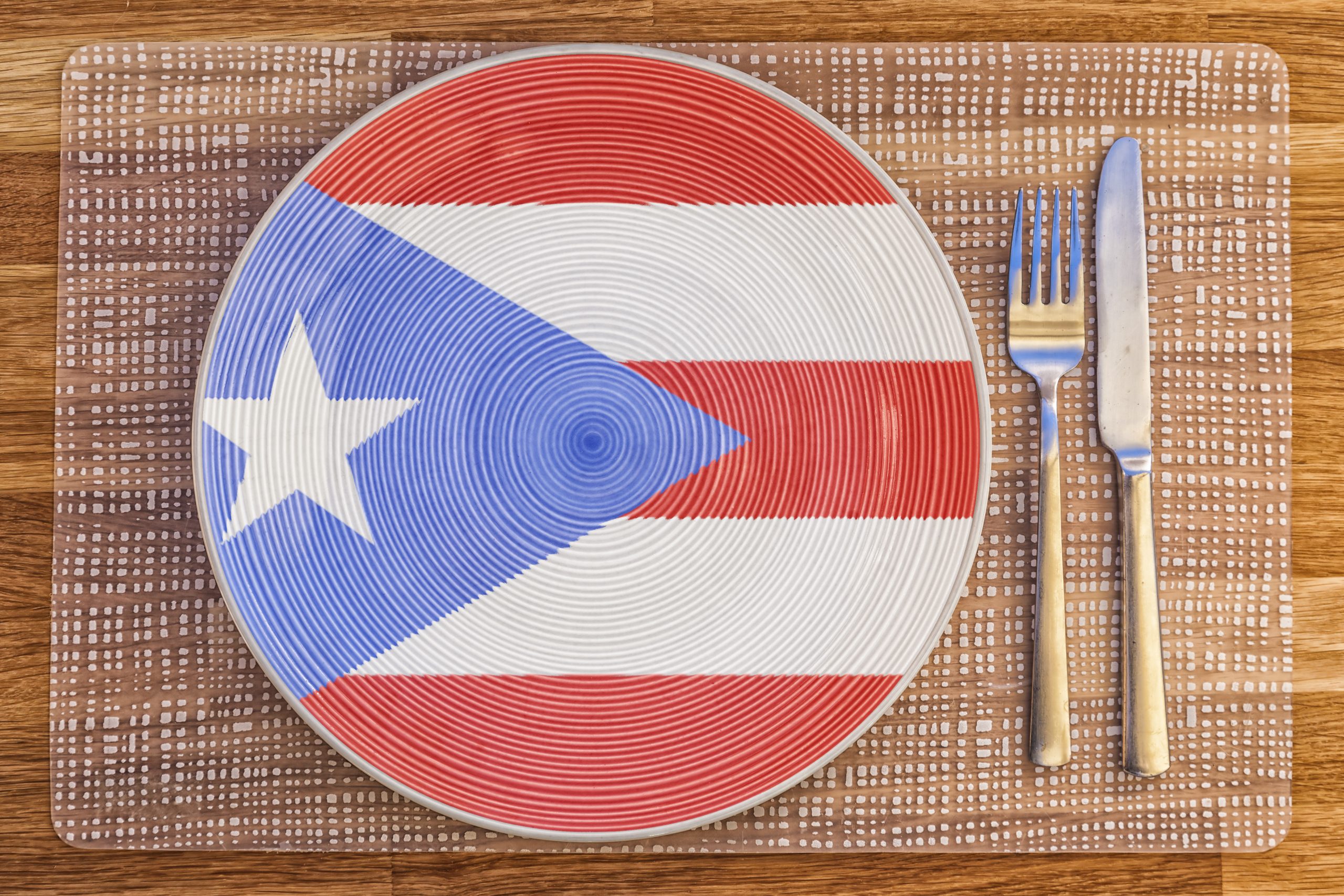 A plate painted with the Puerto Rican flag, next to a fork and knife