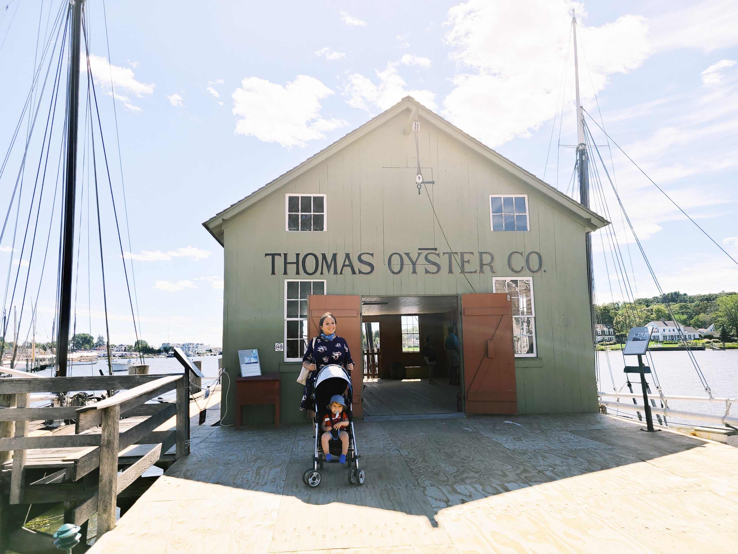 A woman and a child in a stroller stand in front of a building labelled "Thomas Oyster Co."