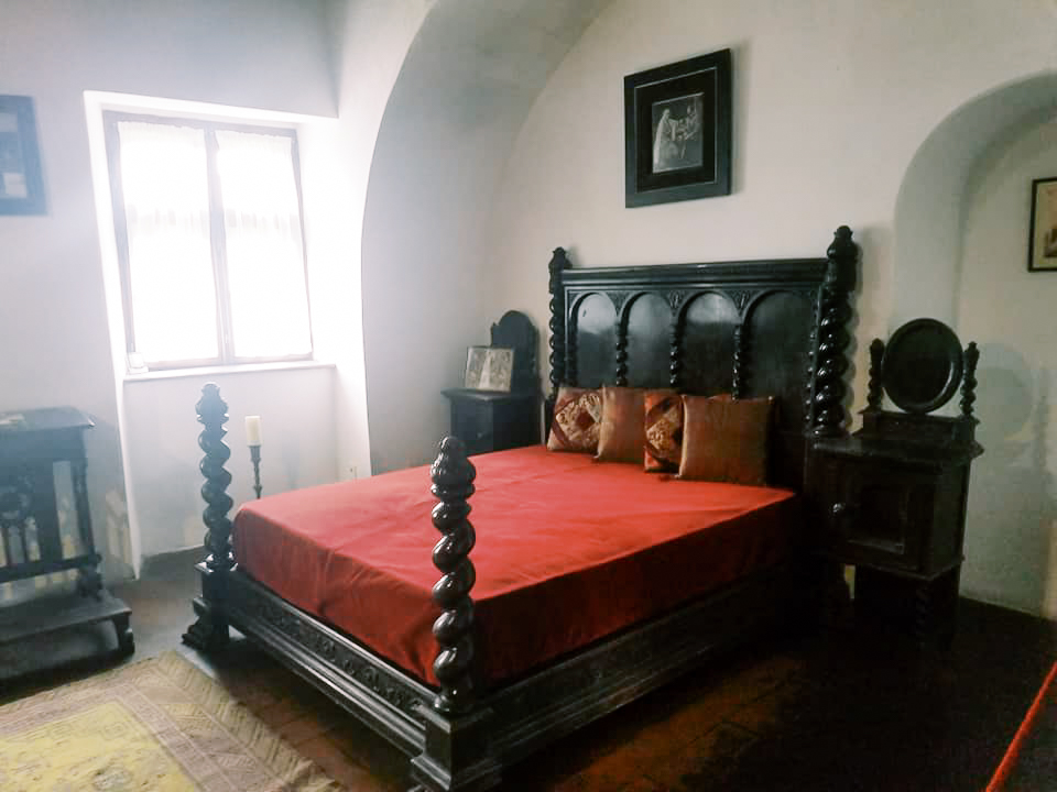 A dark wood bed with red covers